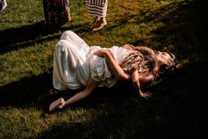 Tochter liegt auf Mutter am Boden bei einer Taufe am Ende der Familienfeier