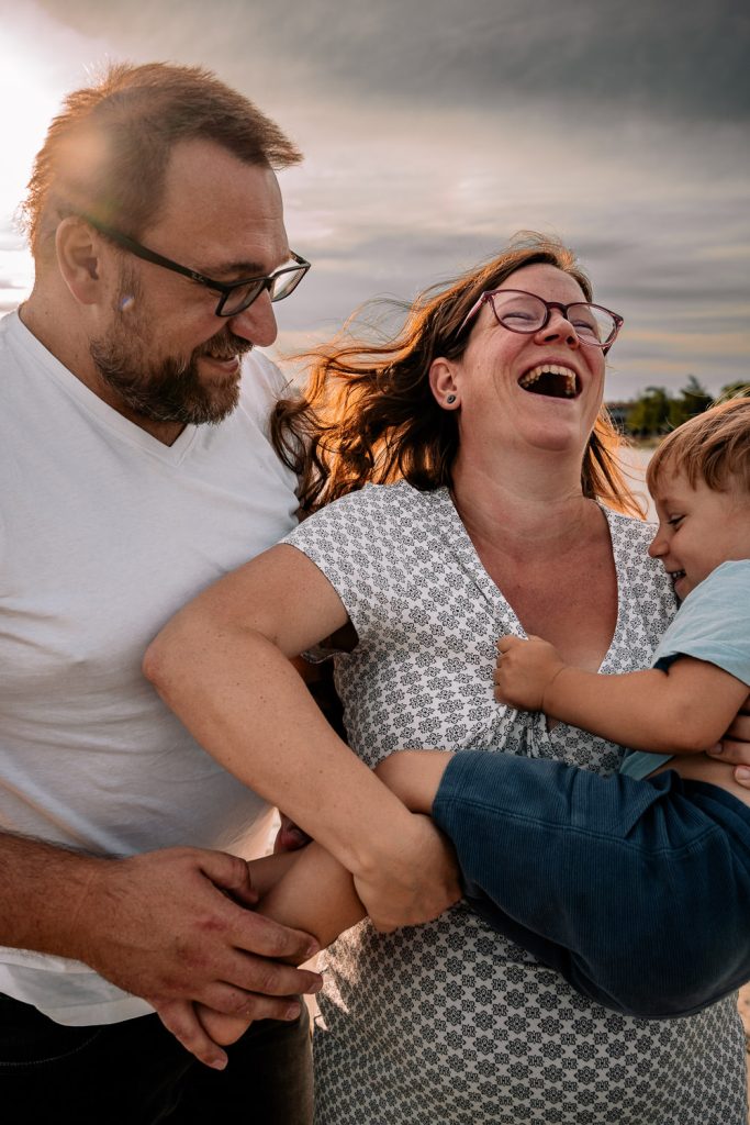 Kind kuschelt mit Mama und Papa Familienfotos