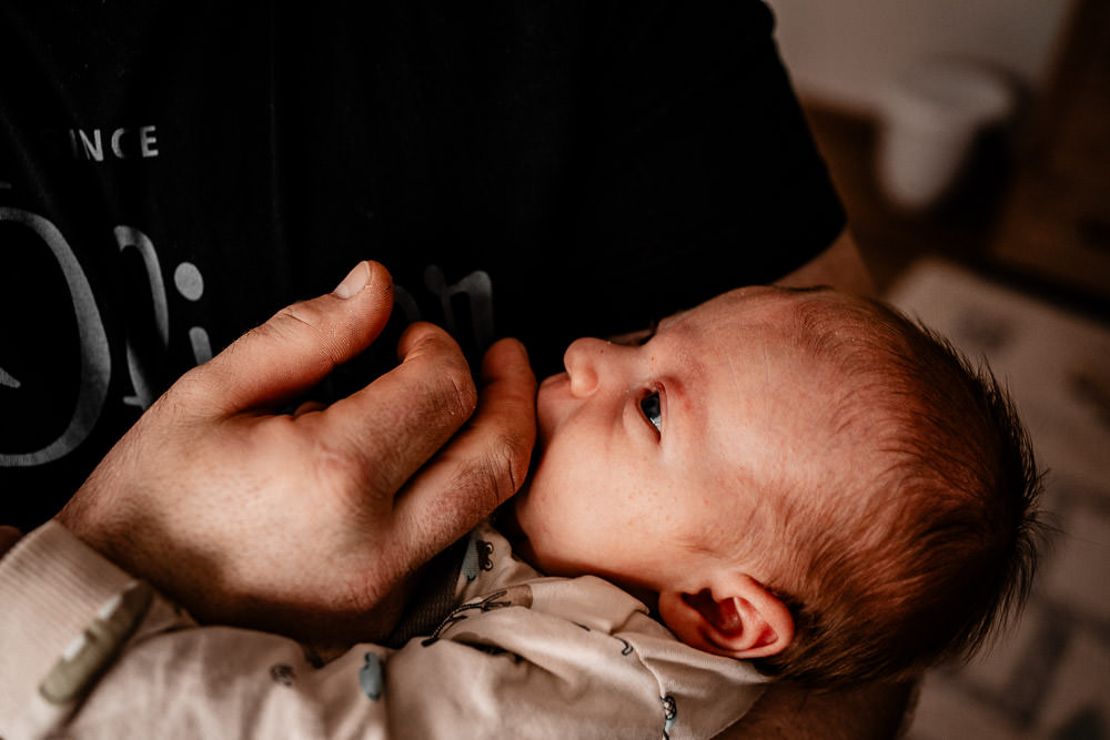 Baby nuckelt an Hand von Papa
