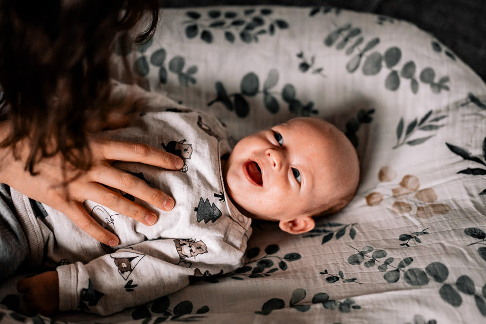 Fotobesuch im Wochenbett 5 Baby frisch geboren im Wochenbett mit Hand der Mutter auf dem Bauch