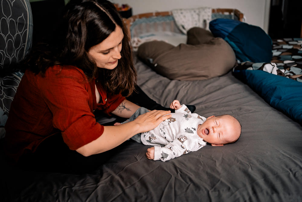 Fotobesuch im Wochenbett 12 Mutter schaut auf Neugeborenes welches gähnt