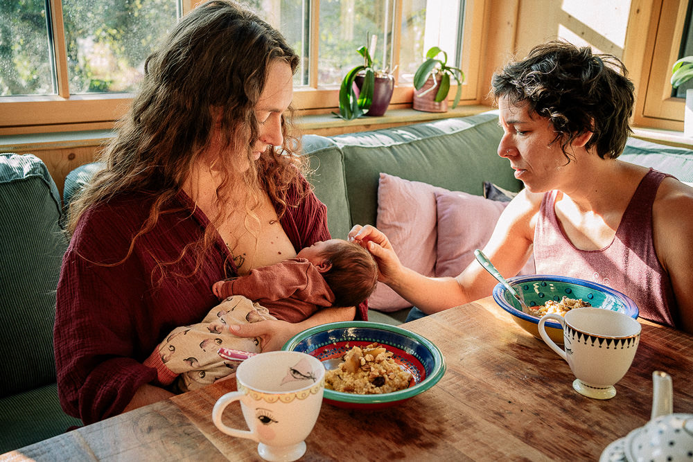 Mamas frühstücken gemeinsam mit Baby auf dem Arm beim Wochenbettshooting