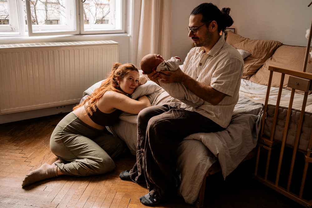 Eltern mit Neugeborenem im Wochenbett bei Fotobesuch Wochenbettfotografin